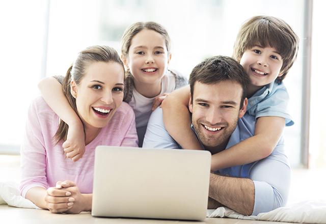 Mother, father and two children lying in front of an open laptop